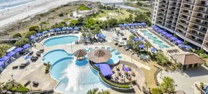 Un resort con diverse piscine, lettini e ombrelloni.