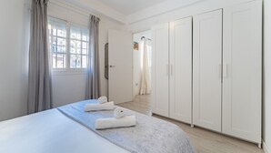 Une chambre à coucher avec un lit, une armoire et une salle de bain visible à travers une porte ouverte.