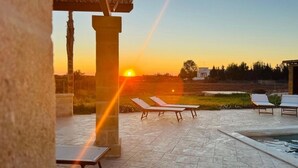 A sunset view from a patio with lounge chairs and a swimming pool. - Villa Rakorishia Vu~ira rakorishia (Puglia)