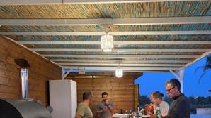 An outdoor wooden structure with a grill and a counter, surrounded by a wooden fence and a gravel ground. - Villa Rakorishia Vu~ira rakorishia (Puglia)