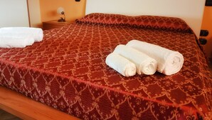 A neatly made bed with a patterned bedspread and two rolled towels on it. - Villa Rakorishia Vu~ira rakorishia (Puglia)