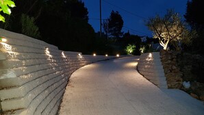 Eine gepflasterte Straße, an einer Seite eine Steinmauer und an der anderen ein Baum.
