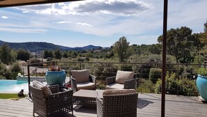 Eine Terrasse mit Korbmöbeln und Blick auf einen Pool und Berge.