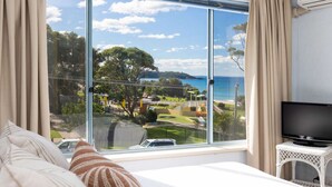 A bedroom with a large window offering a view of a park and beach. - Breakers 2 - Beautiful bright apartment 50m to the sand (Mollymook)