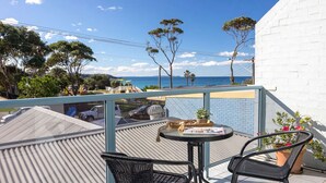 A balcony with a table and chairs, overlooking a parking area and a view of the sea. - Breakers 2 - Beautiful bright apartment 50m to the sand (Mollymook)