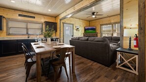 Un interno in legno con un tavolo da pranzo apparecchiato per quattro persone, un divano e una ventola a soffitto.