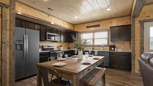 Ambiente in legno con cucina, tavolo da pranzo e zona salotto.