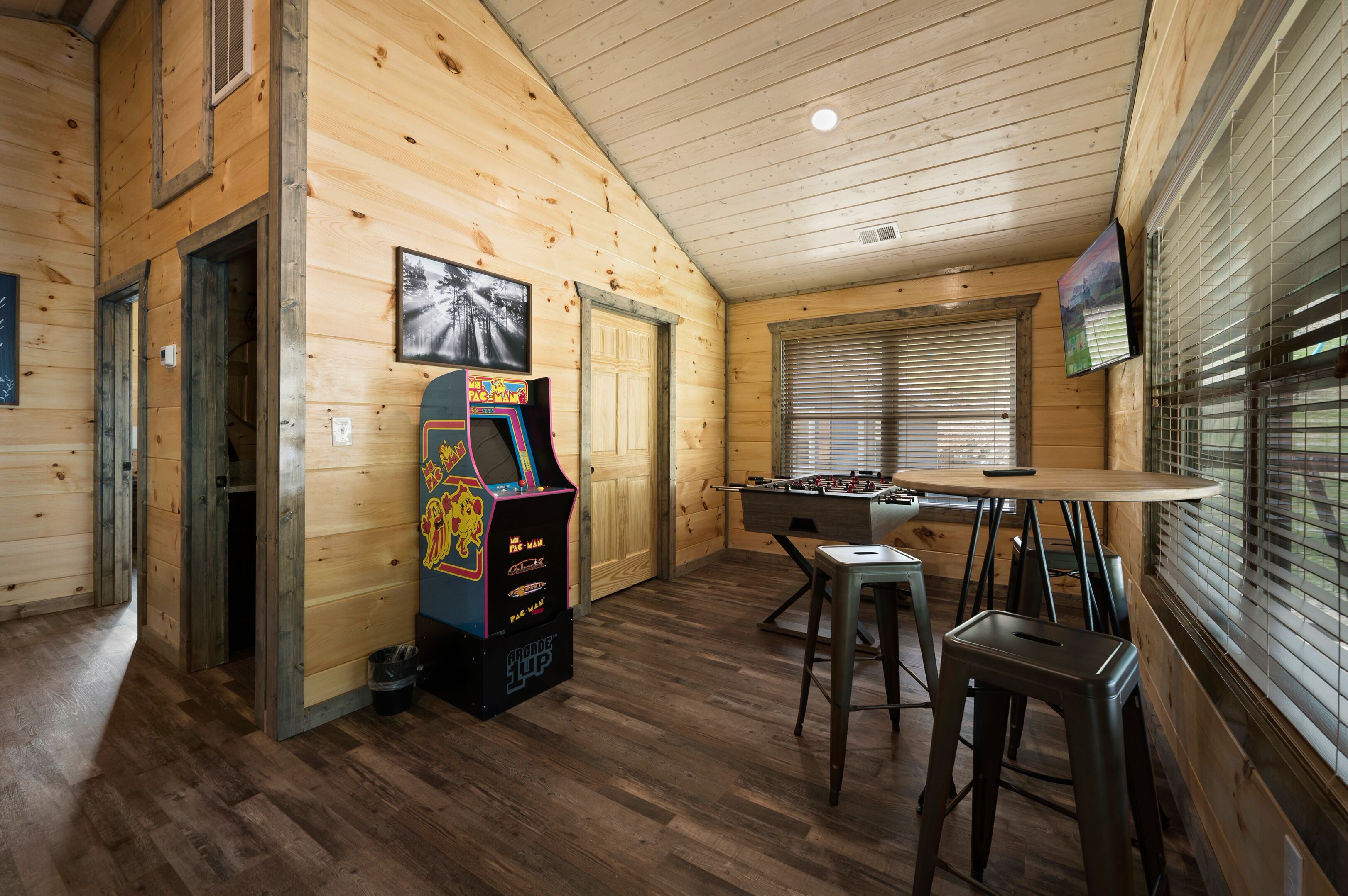 Una stanza accogliente con pareti in legno, un tavolo da calcio e un'arcade Pac-Man.