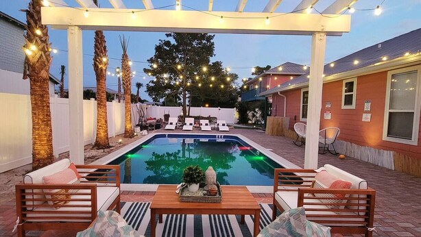 Area piscina con una pergola, sedie a sdraio e un tavolo con oggetti decorativi.