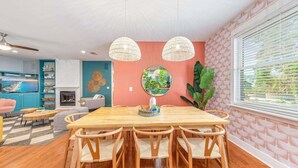 Zona pranzo con tavolo e sedie in legno, un grande specchio e un lampadario.