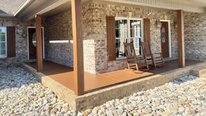 Ein Haus mit verdeckter Veranda, Ziegelmauern und einem Stein Fundament.