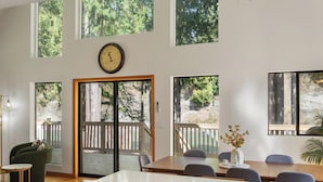 Un intérieur moderne comprenant un coin repas, de grandes fenêtres et une vue sur une terrasse en bois.