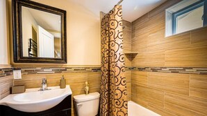 A bathroom with a sink, toilet, and bathtub. - Luxury Studio Suite. Walking distance to UBS Arena (Elmont)