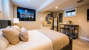 A bedroom with a bed, a nightstand, a desk, and a window. - Luxury Studio Suite. Walking distance to UBS Arena (Elmont)