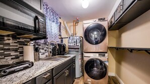 A compact kitchen with a built-in washer and dryer, a microwave, and a coffee maker. - Luxury Studio Suite. Walking distance to UBS Arena (Elmont)