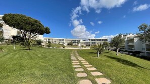 Um edifício moderno com um pátio central, rodeado por relva bem cuidada e árvores.