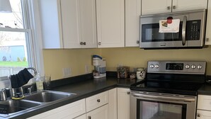 A modern kitchen with white cabinets, stainless steel appliances, a double oven, and a microwave.