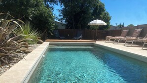 A rectangular swimming pool with clear water, surrounded by a wooden deck and lounge chairs. - Beautiful villa near Uzès (Blauzac)
