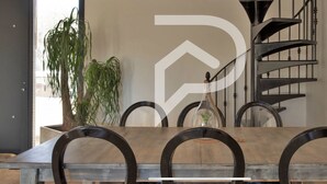 A dining area with a wooden table and black chairs, a spiral staircase, and a potted plant. - Beautiful villa near Uzès (Blauzac)