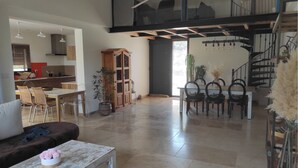 A spacious living area with a dining table, chairs, a sofa, and a staircase leading to an upper level. - Beautiful villa near Uzès (Blauzac)