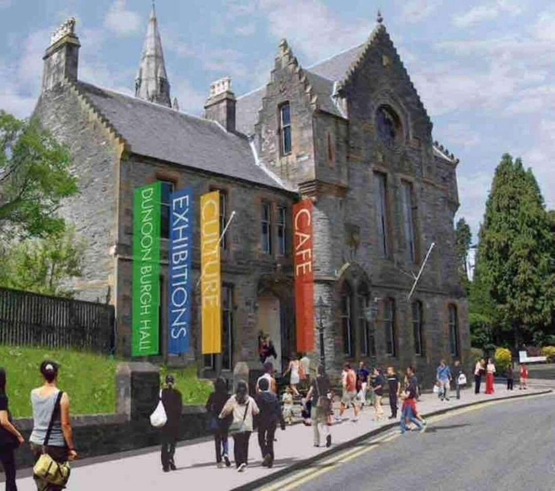 A historic stone building with banners advertising exhibitions and a café.