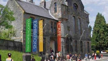 A historic stone building with banners advertising exhibitions and a café.