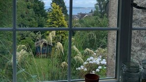 Uma janela com vista para um jardim e paisagem distante.