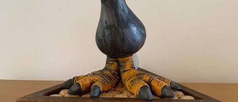 A sculpture of a bird with a curved beak, resting on a wooden base.