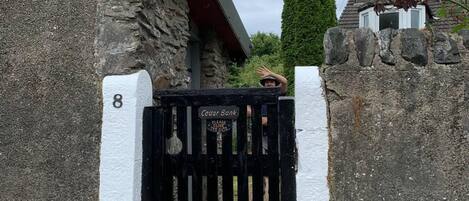 Una entrada protegida con muro de piedra y portón metálico.