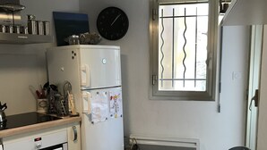 A kitchen with a Bosch oven, a refrigerator, a clock, and a window with bars.