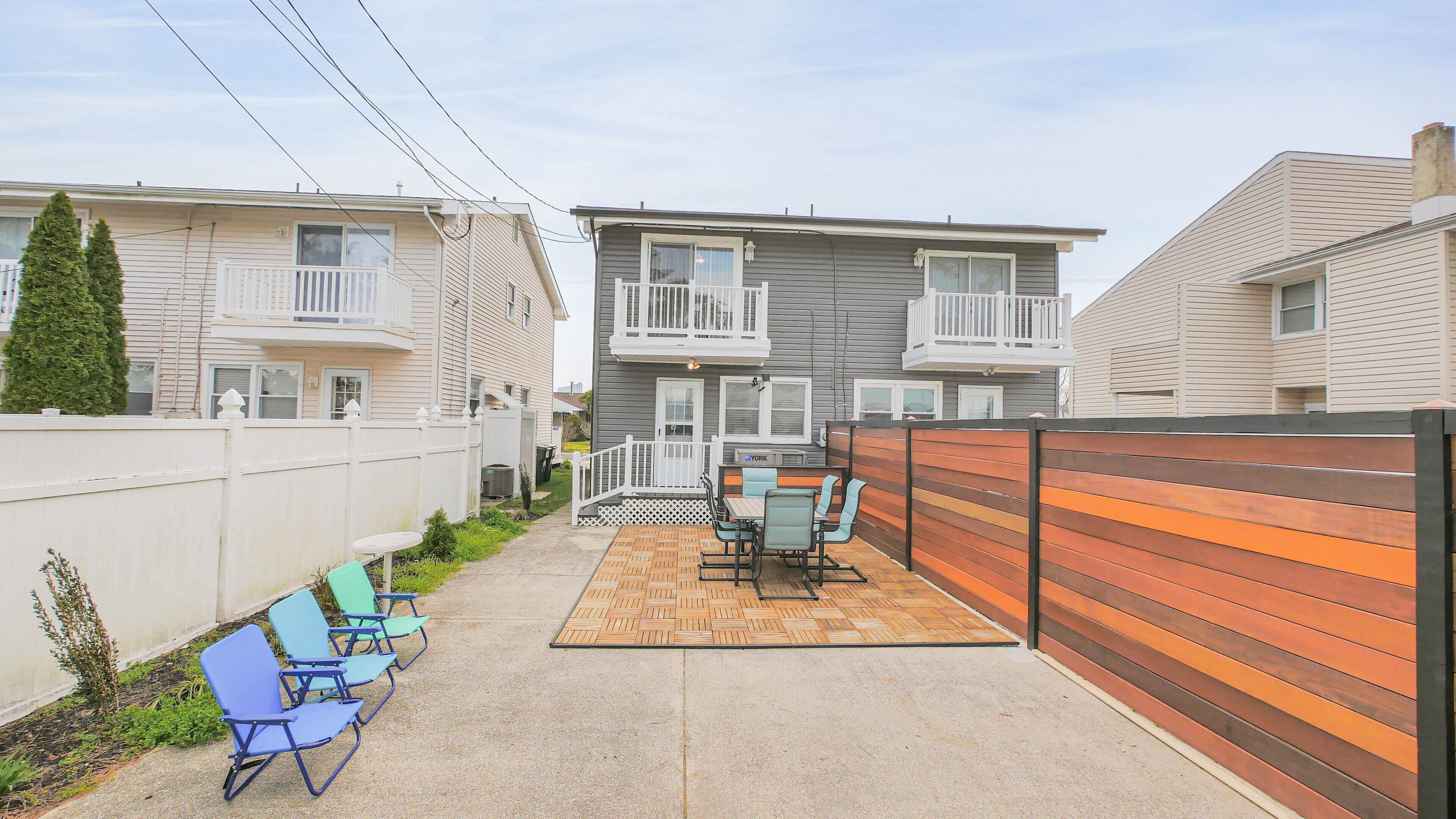 A patio area with a table and chairs, a wooden fence, and a view of adjacent buildings.