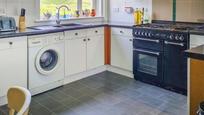 A kitchen with a washing machine, a stove, and a sink. - Craik Forestry Cottage (Craik, near Hawick)