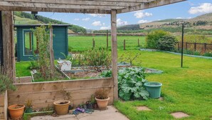 A garden with raised beds, a wooden pergola, and a green shed. - Craik Forestry Cottage (Craik, near Hawick)