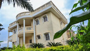 A multi-story building with balconies, surrounded by lush greenery. -  Manoir Des Innoncents (Bafoussam)
