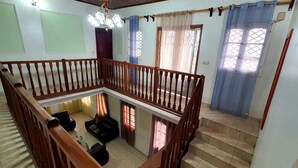 A multi-level living space with a wooden staircase, a balcony, and a chandelier. -  Manoir Des Innoncents (Bafoussam)
