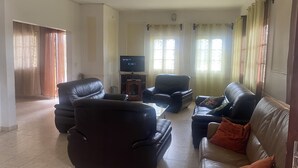 A living room with a sofa, armchairs, a coffee table, and a TV. -  Manoir Des Innoncents (Bafoussam)