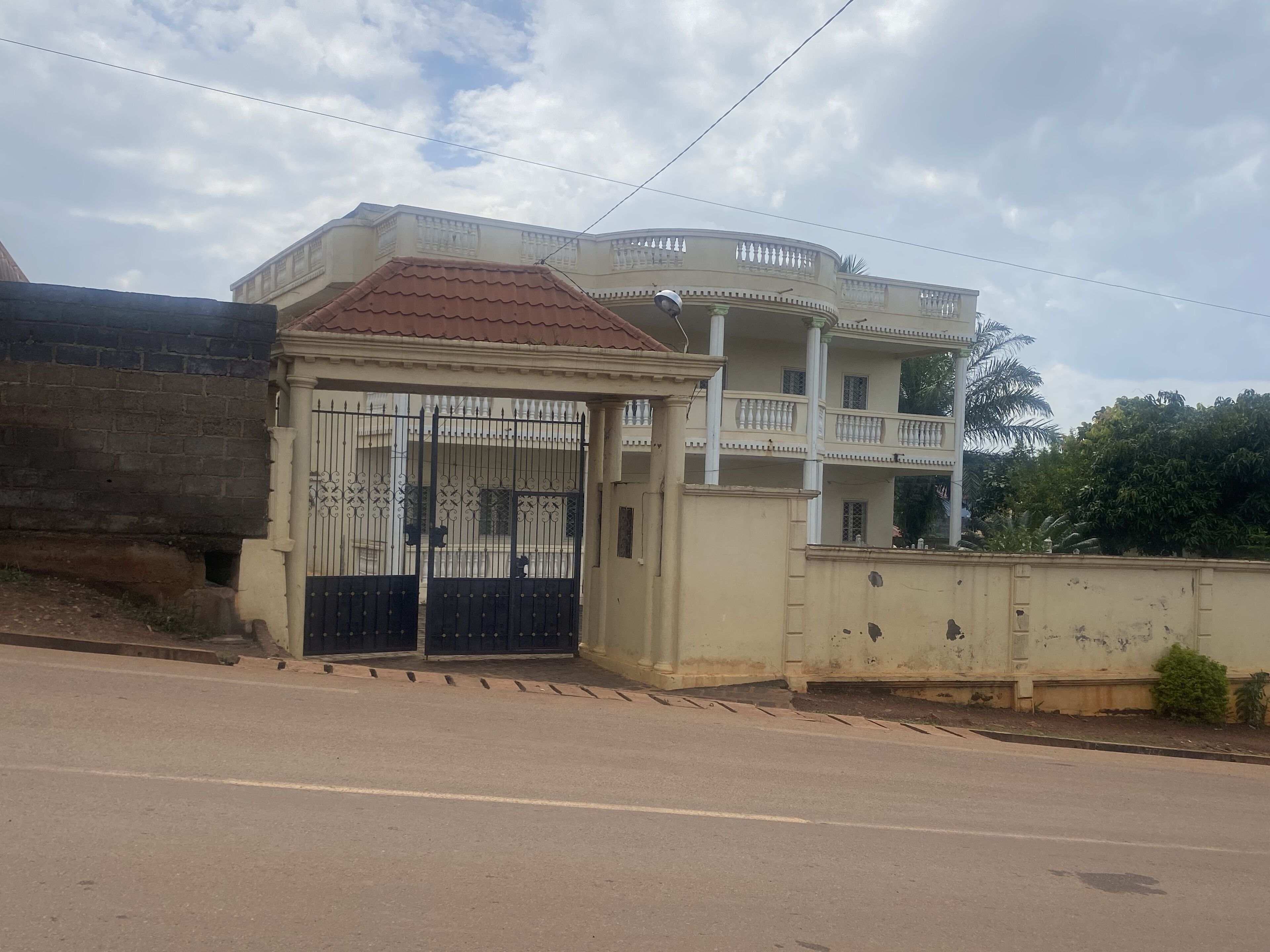 A two-story building with a gated entrance and a balcony on the upper floor.