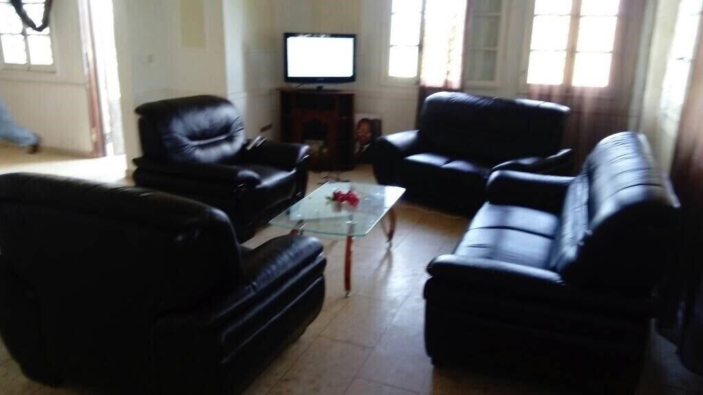 A living room with black leather sofas, a glass coffee table, and a television on a stand.