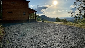 Una cabaña de madera con camino de grava y una vista panorámica a la montaña.