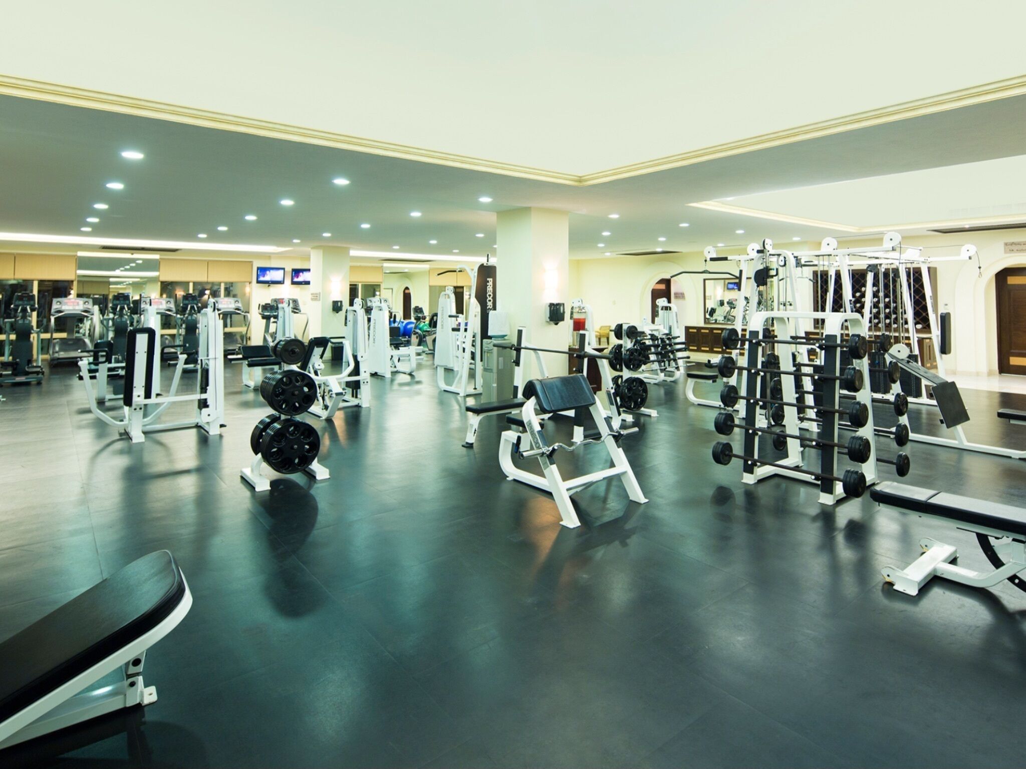 A spacious gym with various exercise equipment, including weight machines and free weights.