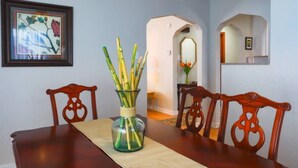 Ein Esszimmer mit Holztisch, Stühlen, einer Vase mit Bambus und einem gerahmten Bild an der Wand.