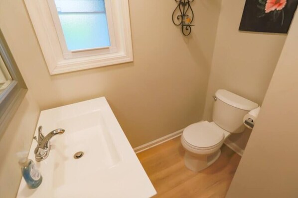 A small bathroom with a white sink, a toilet, and a window above the sink. - 4 Bed Cape Cod | Comfort & Charm Near the City (Pittsburgh)