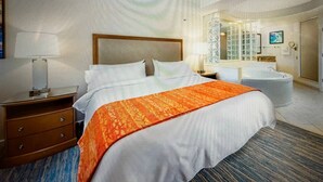 A hotel room with a large bed, a wooden nightstand, a desk, a bathroom with a bathtub, and a large mirror. - Marriott Cypress Harbour resort (Orlando)