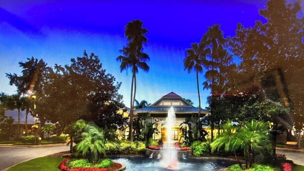 A hotel with a central fountain, surrounded by manicured gardens and palm trees. - Marriott Cypress Harbour resort (Orlando)