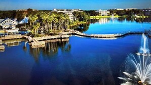 A large body of water with a bridge, palm trees, and buildings in the background. - Marriott Cypress Harbour resort (Orlando)