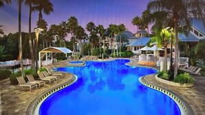A large, circular swimming pool surrounded by lounge chairs and palm trees. - Marriott Cypress Harbour resort (Orlando)