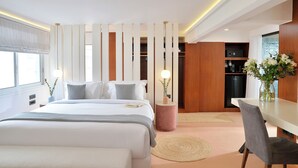 Ett modernt hotellrum med en stor säng, sängbord, ett skrivbord och utsikt över staden.