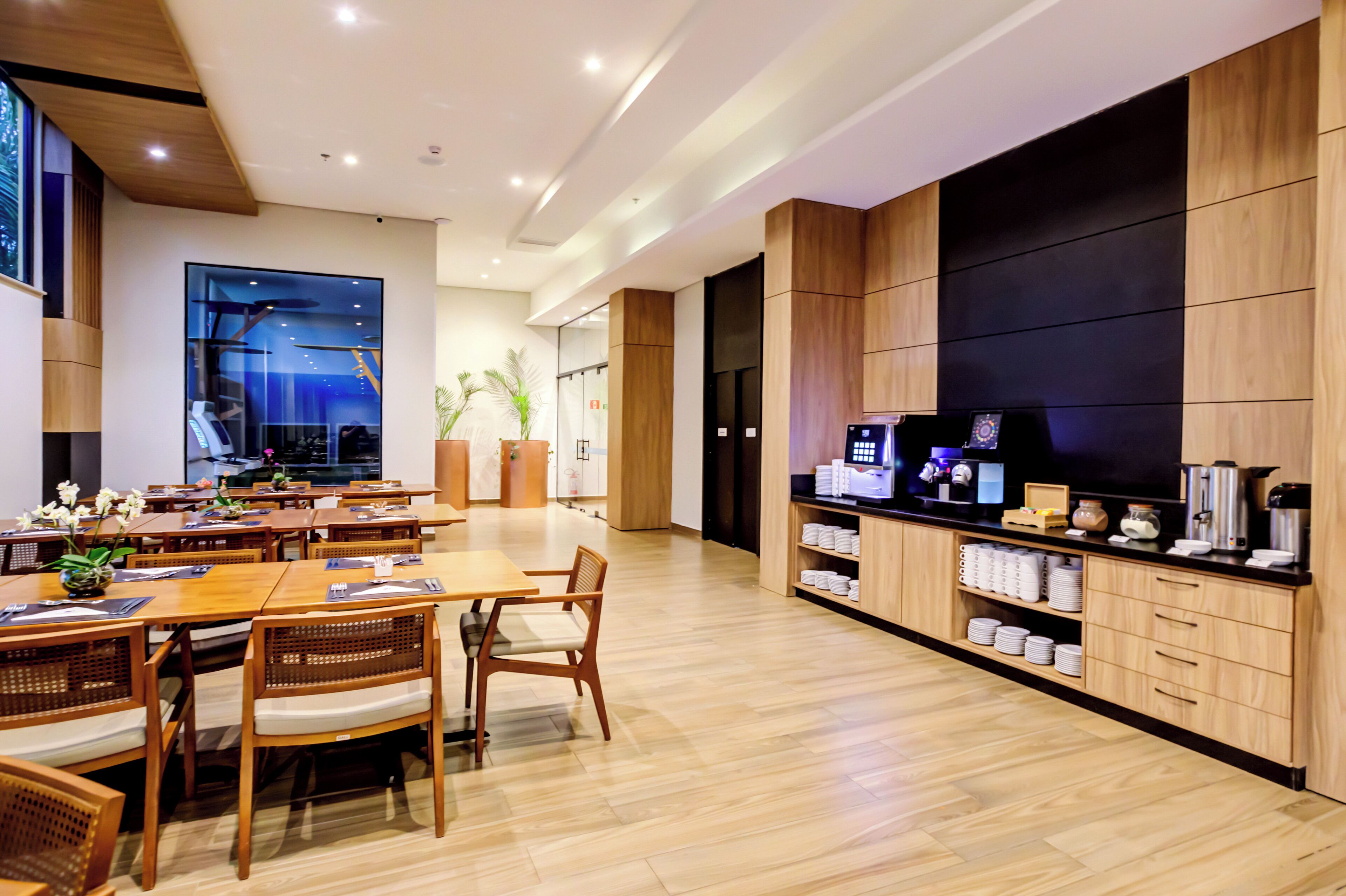 Een moderne hotel lobby met houten vloeren, een receptiebalie en een zithoek met tafels en stoelen.