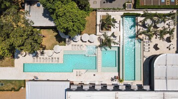 Vista aérea de un hotel con varias piscinas, tumbonas y sombrillas.