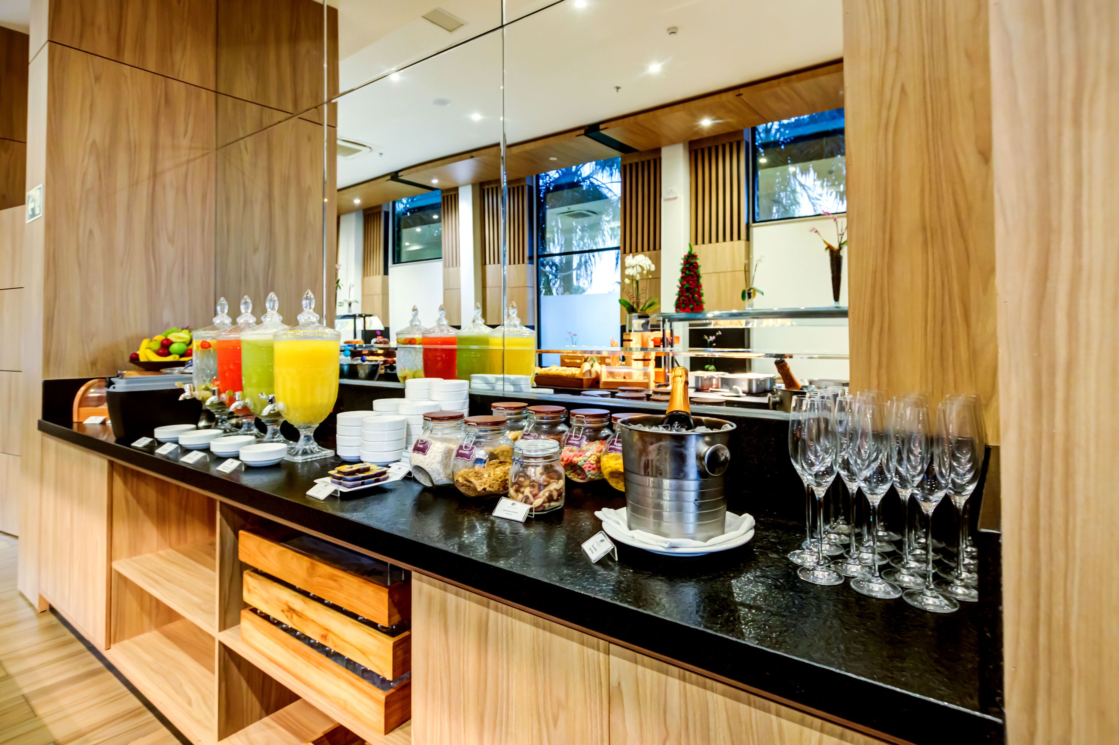 A breakfast bar with various food items, drinks, and a selection of wine glasses.